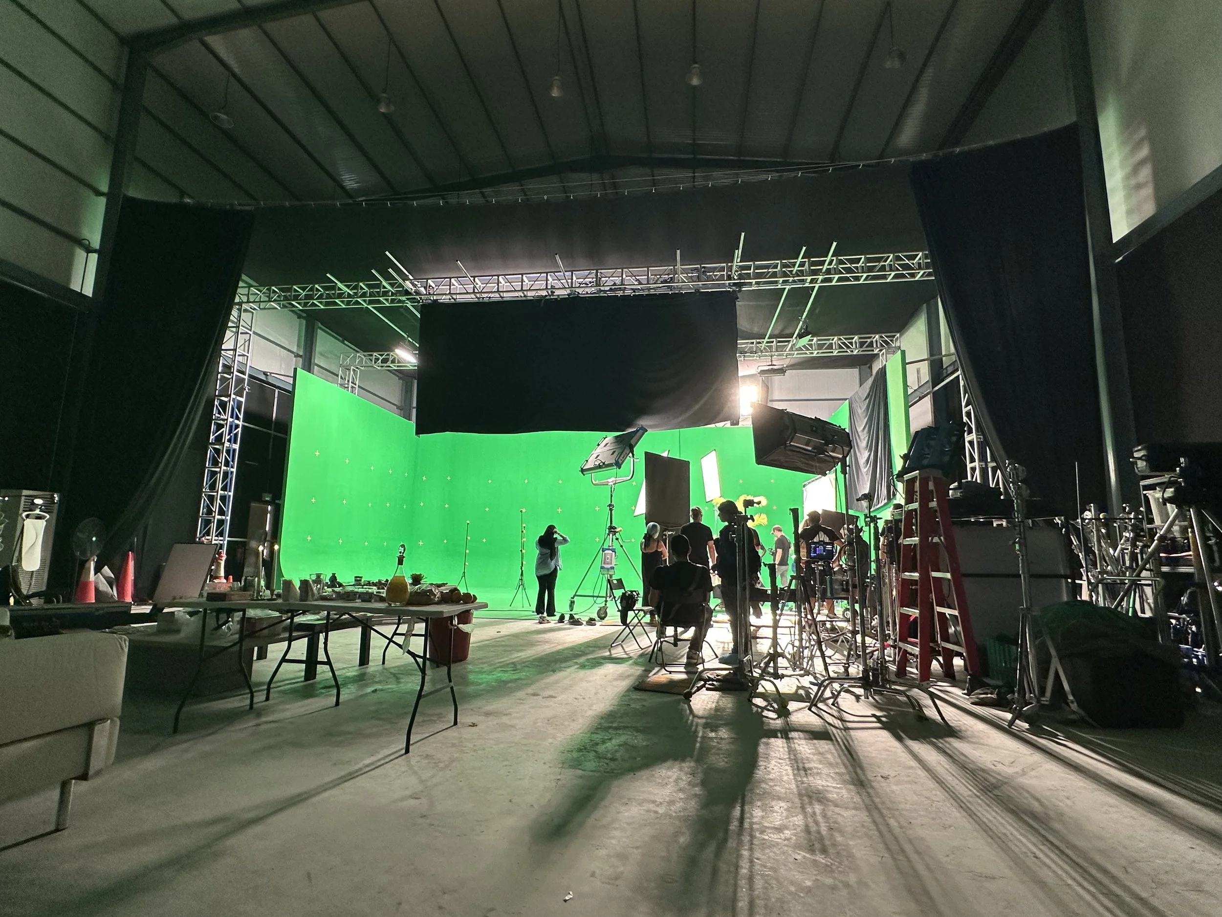 Crew, cameras and lighting positioned around a green screen stage